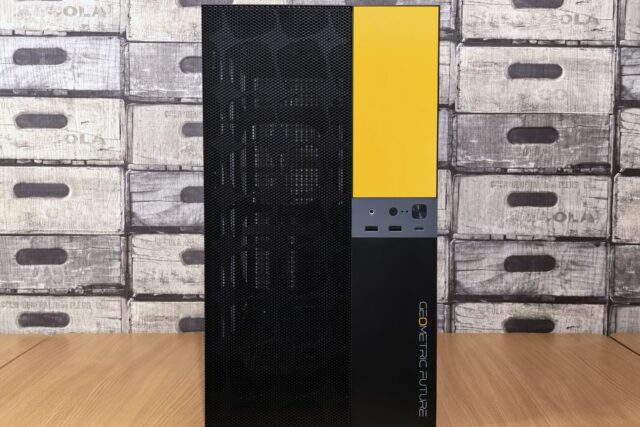 Calculator desktop cu carcasă aerisită, așezat lângă un monitor și o tastatură pe un birou luminos