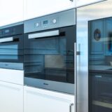 Bucătărie modernă cu frigider, cuptor și mașină de spălat vase încorporate în mobilier deschis la culoare